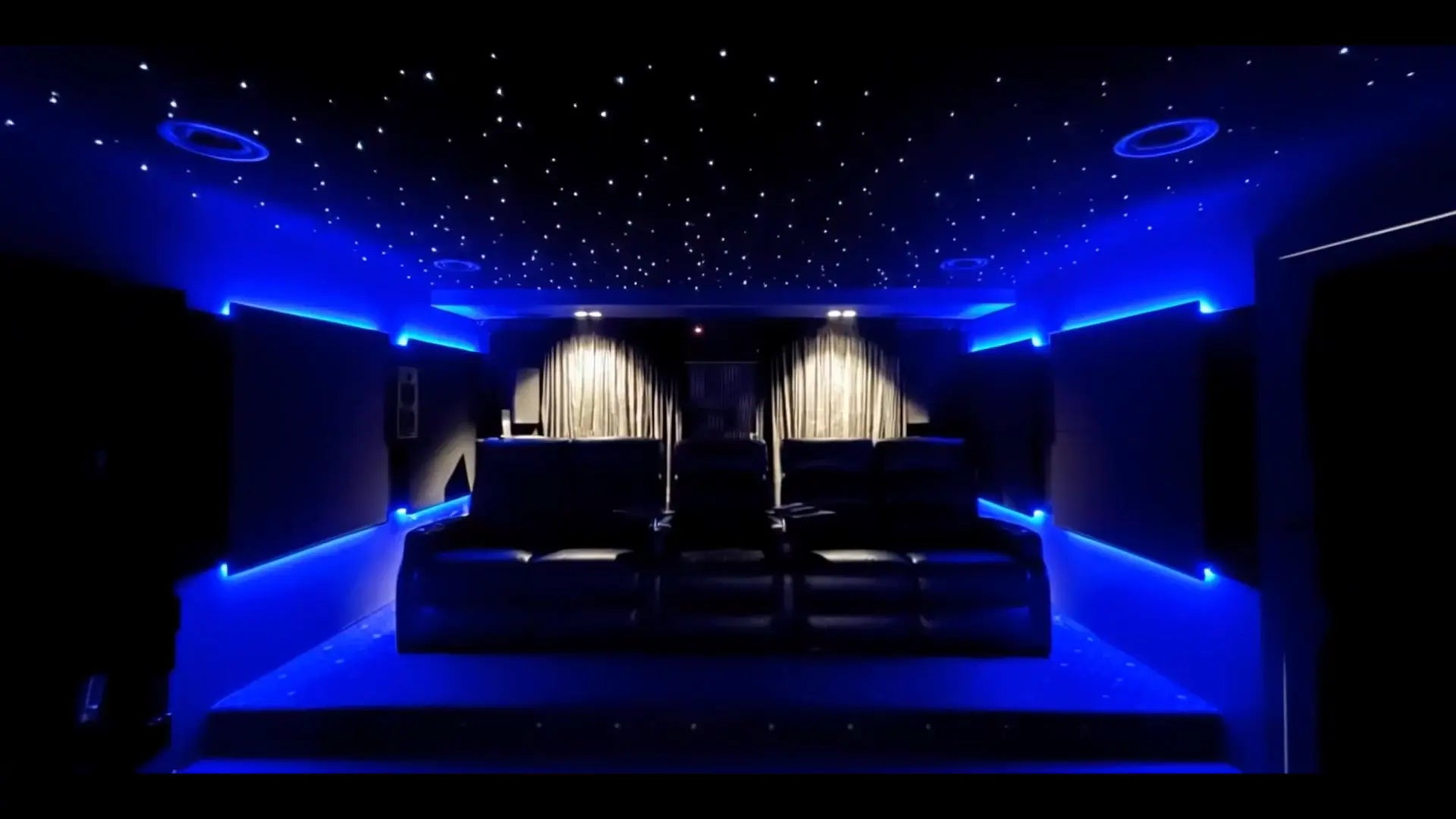 A cinema room by Sydney Hi-Fi lit in blue, with a starfield ceiling and two rows of recliners